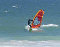 On your way towards the shore, look for a swell wave that is building up and adapt to its speed. Drop slightly on the wave face to reduce the pull in the sail and make the following side change easier. Place your front foot in front of the mast foot and release your back hand from the boom to grab the new boom side.