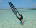 2) Turn into the wind until the board is facing into it, then push the sail forwards towards the bow as you would for a helicopter tack – it will luff, and the board will turn out of the wind.