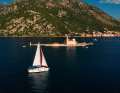 Yacht de location devant Gospa od Skrpjela, en français : Marie du Rocher. En arrière-plan, la ville portuaire de Perast
