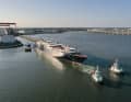 Tugboats pull the half-finished "Orient Express Corinthian" out of the dock.