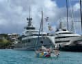 Un netto contrasto: Adam Waugh con il suo "Little Wren" davanti a yacht di lusso nei Caraibi.