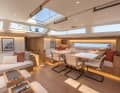 Vista aperta sul salone grazie al vetro frontale, con zona salotto coperta e tavolo da pranzo in un ambiente ispirato a uno studio.