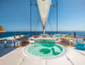Flybridge : pendant que le capitaine s'occupe du réglage des voiles à l'avant du poste de pilotage, les invités profitent de la vue au bar jacuzzi. Il n'y a pas de meilleur endroit pour boire son cocktail - selon la gîte, il est également possible de barboter pendant le voyage.