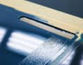 Unclean: residue from an adhesive strip causes the paint to bead up. Clean the substrate with thinner and silicone remover