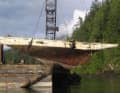 Après avoir été récupérés avec succès au fond du lac Pitt, les restes du yacht de course sont suspendus à une grue.