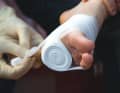 Only unwind a small part of the bandage, the bandage itself serves as a compress. Use the unwound part to press the bandage firmly onto the wound