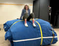 Angela Abshier sits on a sail package weighing several tonnes.