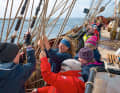 Jugendarbeit: Trainees und eine Deckshand der Stammcrew bedienen Geitaue und Gordinge. Auf der „Roald“ wird traditionelle Seefahrt gelehrt.