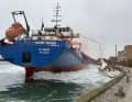 The cargo ship squeezed the sailing boat and snapped the mast with the bridge nose. The crew deployed a distress buoy but did not sound any audible signal.