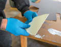 Dents fines : pour appliquer la colle de manière uniforme, il faut utiliser une spatule à dents fines. Si l'outil est trop grossier, comme c'est le cas pour la pose de carrelage, la couche de colle sera trop épaisse et ne pourra pas être pressée uniformément. Le revêtement devient ondulé. Dans le pire des cas, le matériau se casse lorsqu'on essaie de le lisser en forçant. La colle à dispersion AF 270 d'Ardex que nous utilisons sort du seau prête à l'emploi. Mais il est également possible d'utiliser d'autres colles, comme celles que l'on trouve sur le marché pour les revêtements intérieurs