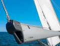 4. Roll up the sail: Slowly release the foot line using the winch  and, ideally with the help of a second person, roll the sail in  as far as necessary. The less the sail flaps,  the fewer creases will form on the mast