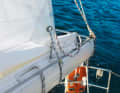 4. Pull the reefing line through: Pull the reefing line tight until the leech is against the boom. In the photo, the reefing line is attached too loosely to the boom; ideally, it should be closer to the boom. Ensure that the reefed sail does not get caught between the boom and the sail. Pull the sheet tight again