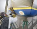 Per Sandstrahl werden Antifouling, Gelcoat und das beschädigte Laminat abgetragen