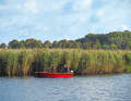 Vorm Schilfgürtel liegen zwei Angler mit ihrem Boot