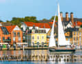 Eine Yacht vor der historischen Kulisse von Kappeln. Direkt davor die Gastliegeboxen, auf der anderen Fahrwasserseite die Heringszäune
