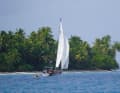 "Holly Golightly" with dinghy in tow crossing the lagoon of an atoll.