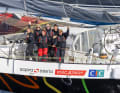 Six of the eight crew members wave from the trimaran, which is designed to carry the women around the world as quickly as possible.