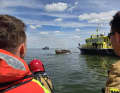A crew member from the KNRM station in Urk and a firefighter from the Urk station watch as the sailing boat is extinguished.