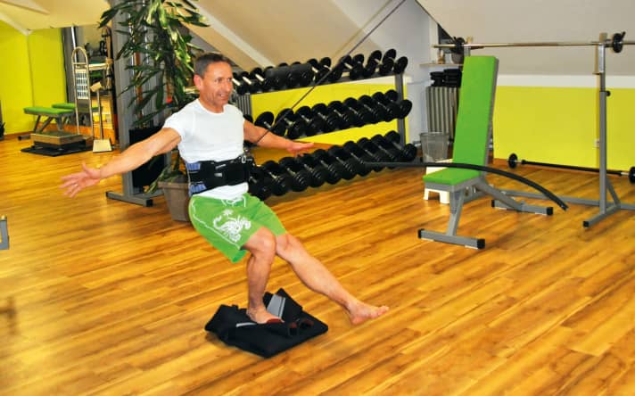 Durch Balancieren und einbeinige Kniebeugen auf einem zusammengerollten Neo stärkst du Hüfte, Knie und Sprunggelenk