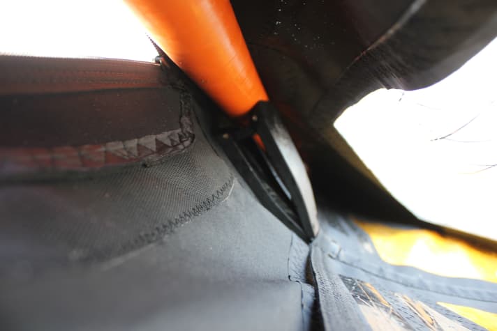 Blick in die Masttasche: Der Camber (schwarz, Bildmitte) sitzt am Mast (orange, oben) und bildet durch den Druck der Segellatte (unten rechts) das Profil.