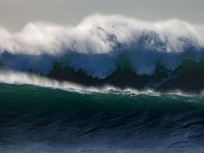 Suchbild mit Surfer – das winzige Masttopp zwischen den beiden Wellen lässt erahnen, dass die Lage ernst ist.