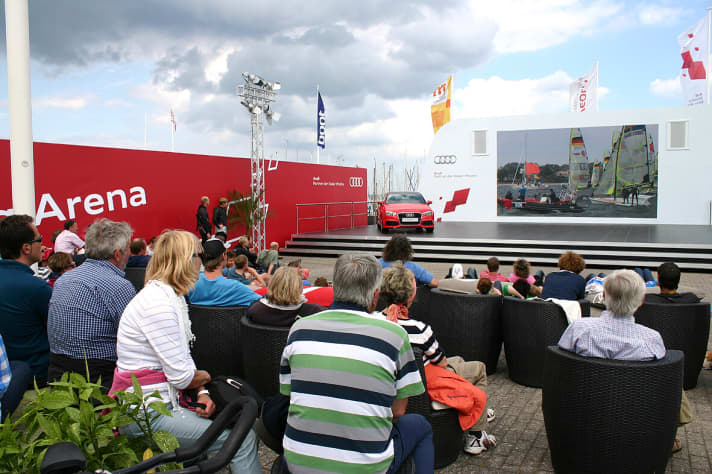   Zu den Finalrennen herrscht hier in der Audi Sailing Arena der Kieler Woche Hochstimmung. Die Veranstalter haben dabei in diesem Jahr auch die gleichzeitig stattfindende Fußball-WM wohlwollend im Blick...