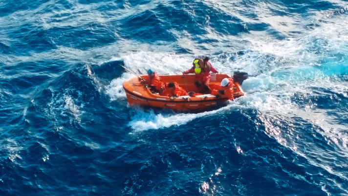   Noch nicht ganz in Sicherheit. Das Boot kehrt zum Containerschiff zurück. Dort wartet auf die Crew das schwierigste Manöver: am Haken schwingend zurück an Bord