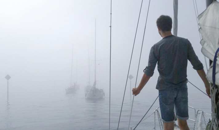  Thick fog has settled on the water. The yachts ahead are only vaguely visible