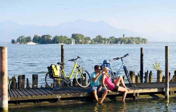Break on the Chiemsee circuit: bike stop in Gstadt with Fraueninsel and Kampenwand in view.
