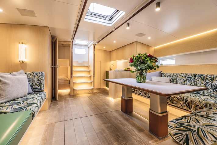 Blick durch den Salon Richtung Heck: An Backbord liegt eine offene Galley, mittschiffs der Niedergang ins Cockpit, an Steuerbord der Eingang zur Gästekabine mit geringer Stehhöhe, daneben verdeckt die Tür zur Tagestoilette