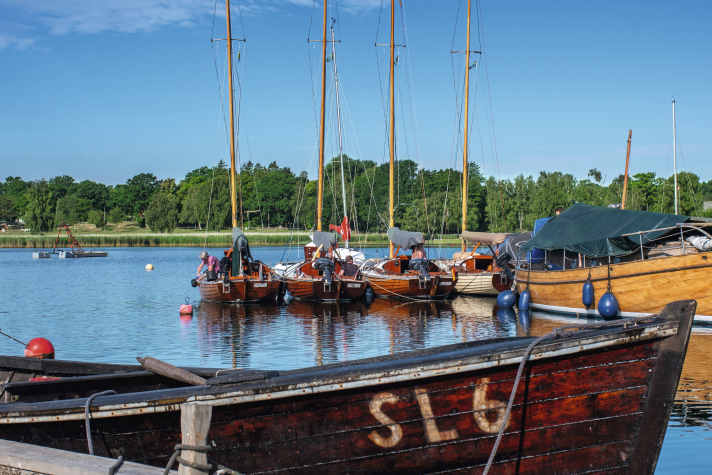 Wooden boats among themselves: the flotilla at the jetty of the museum shipyard in Saxemara