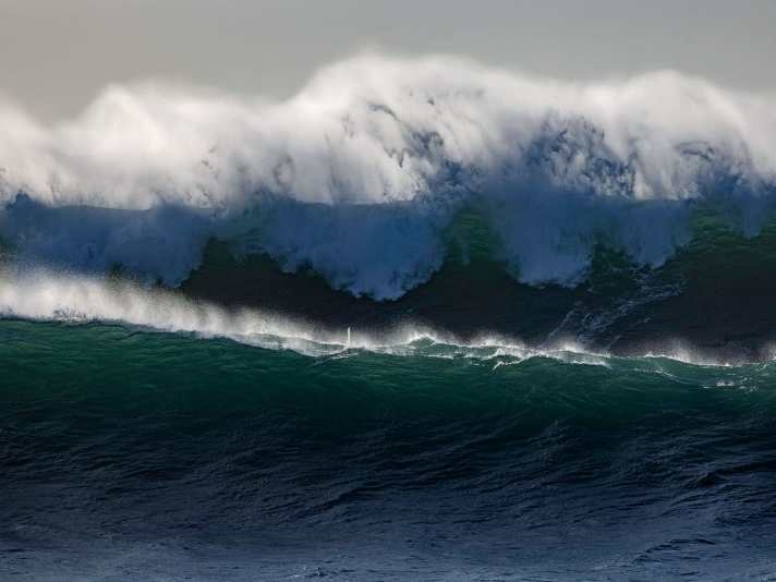 Suchbild mit Surfer – das winzige Masttopp zwischen den beiden Wellen lässt erahnen, dass die Lage ernst ist.