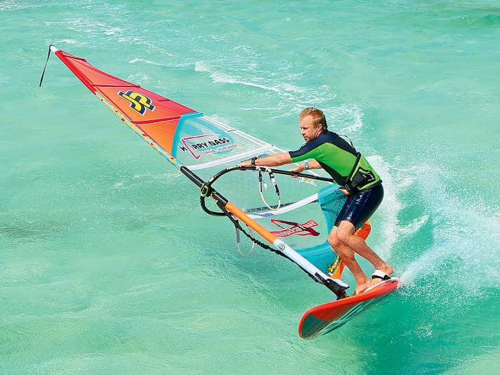 Power jibe or carved jibe: The sail pulls you forwards into a deep turn