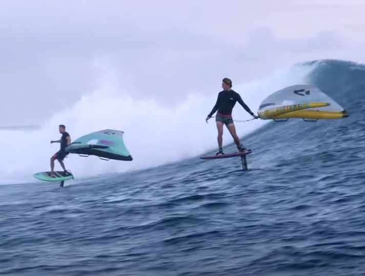 The one who is closer to the breaking part of the wave (left) has right of way - but only if both have "picked" the wave at the same time