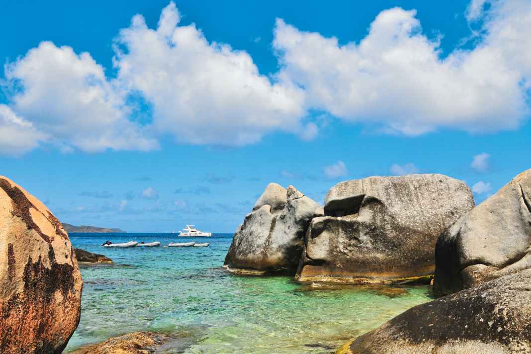 A charter catamaran in front of the striking rock formations of The Baths on Virgin Gorda. The spot is one of the most famous in the entire archipelago