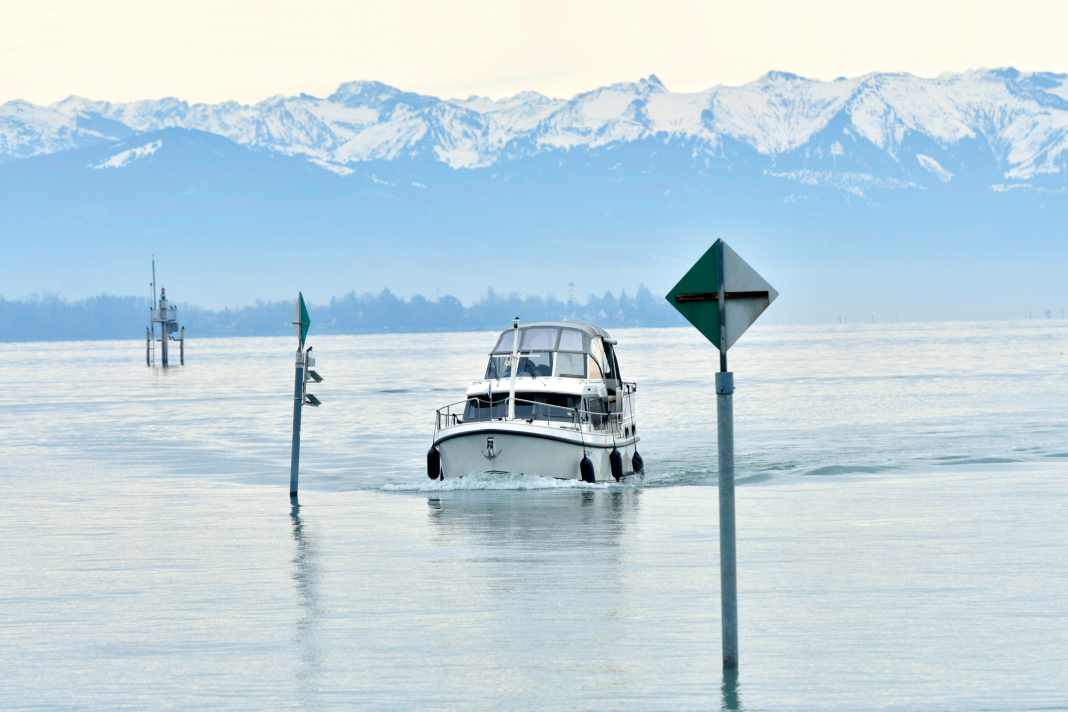 Die schneebedeckten Allgäuer Alpen im Hintergrund: Unser Charterboot läuft in den Hafen von Friedrichshafen ein