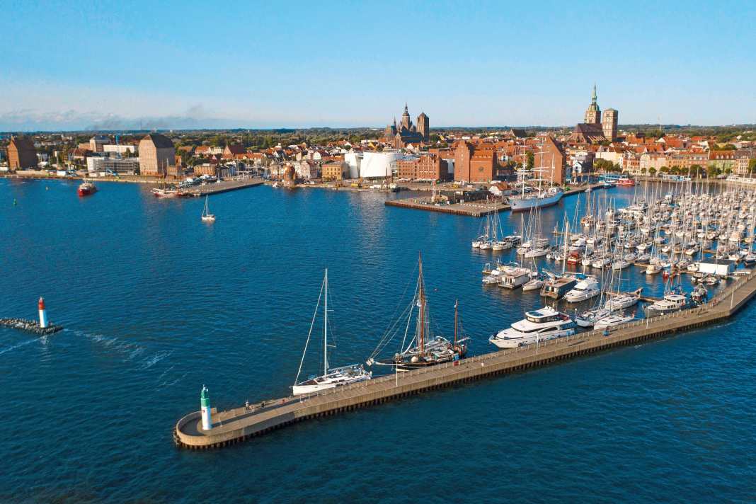 Der Stadthafen von Stralsund mit der Citymarina, den markanten Speichern und der Altstadt dahinter. Die weiße Fassade gehört dem Meeresmuseum Ozeaneum