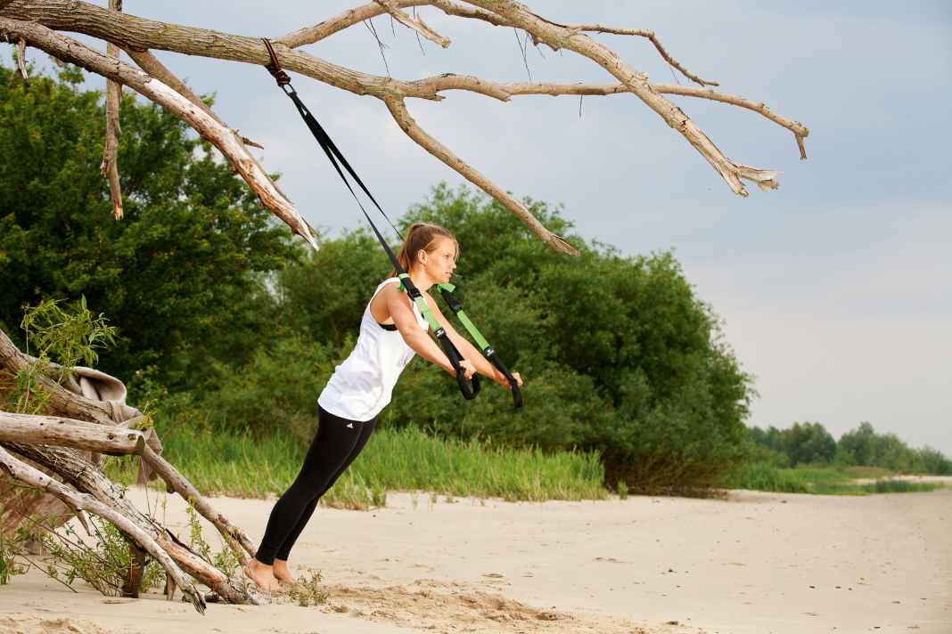 Grip the sling trainer with both hands, straighten your arms and build up body tension