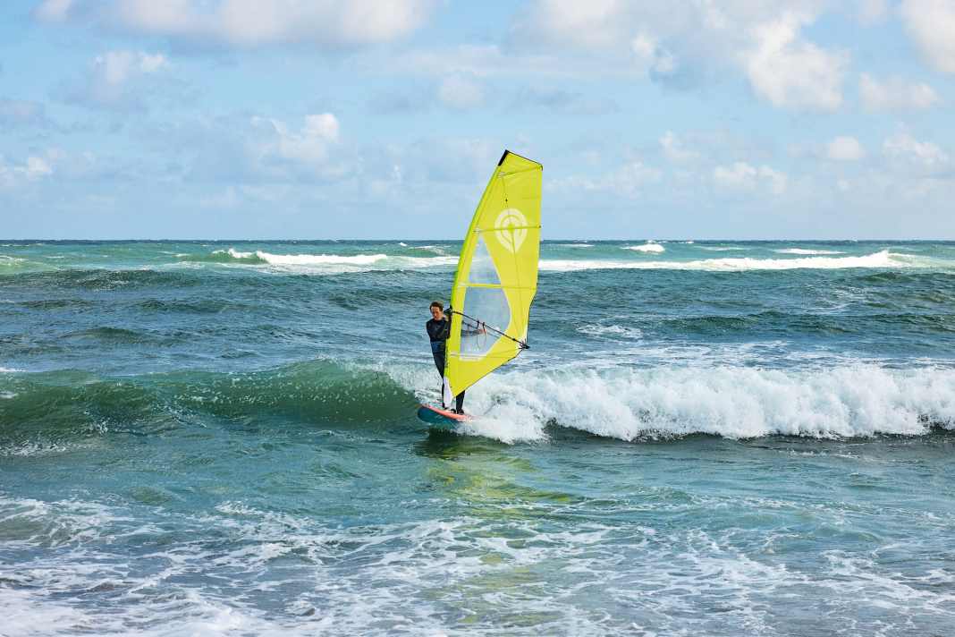 Position yourself at a safe distance on a wave that is building up and surf with it towards the beach