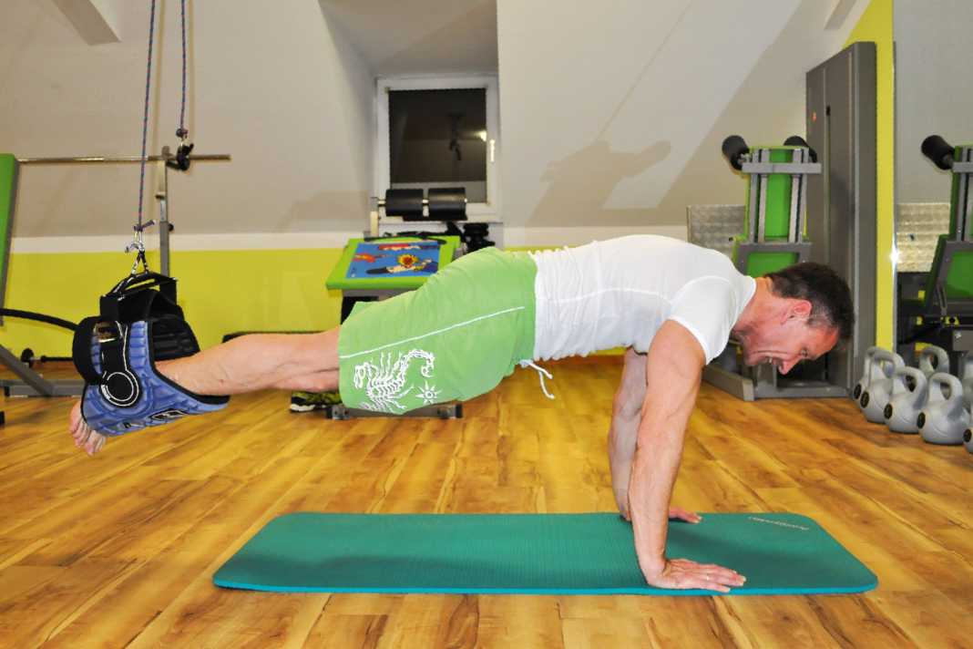 Get into a push-up position and hang your legs on the trapeze