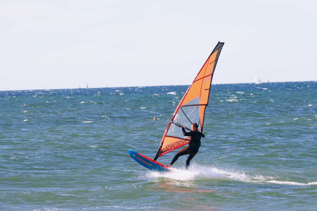 Get as much speed as possible, make sure your feet are firmly in contact with the loops and aim for a small ramp. Ideally, the wave should come from the front and you can hit it head-on on a half-wind course. You can also loop over the back of a wave, but because the wave runs away from you, you need more basic speed to avoid getting stuck on the take-off. A few seconds before take-off, push your sailing hand far back towards the clew and aim for the take-off.