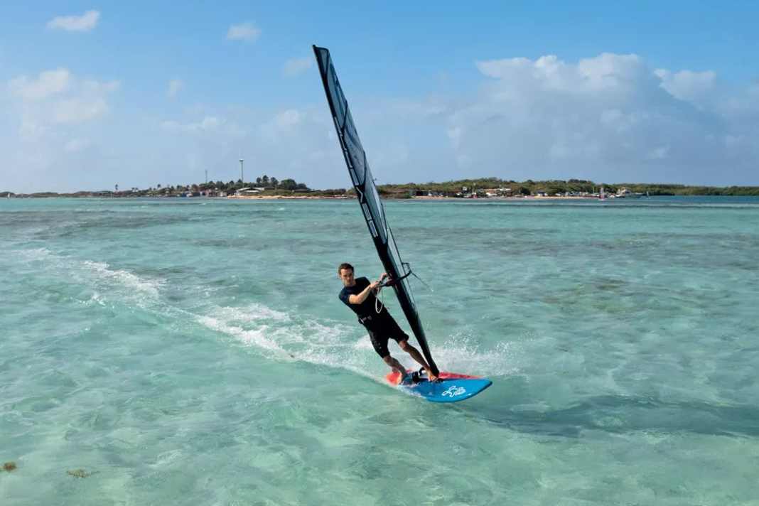 1) The foot change to duck tack takes place before ducking. To make this successful, release some pressure from the sail and change your feet on a light downwind course by first moving your front foot backwards (heel-to-tack) and then immediately moving your back foot forwards towards the foot of the mast. You can initiate the duck tack from half or full planing on a half-wind course. After a successful foot change, luff slightly upwind again.