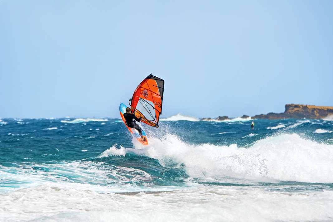 Pick up enough speed on the approach on a light space wind course and unhook from the harness. However, the jump itself should not be too strong on a light headwind, otherwise you will lack the momentum to turn in the air. The ideal take-off is on a half-wind course. In contrast to the spin loop, our photo rider Flo Jung does not grab the fork backwards before the jump.