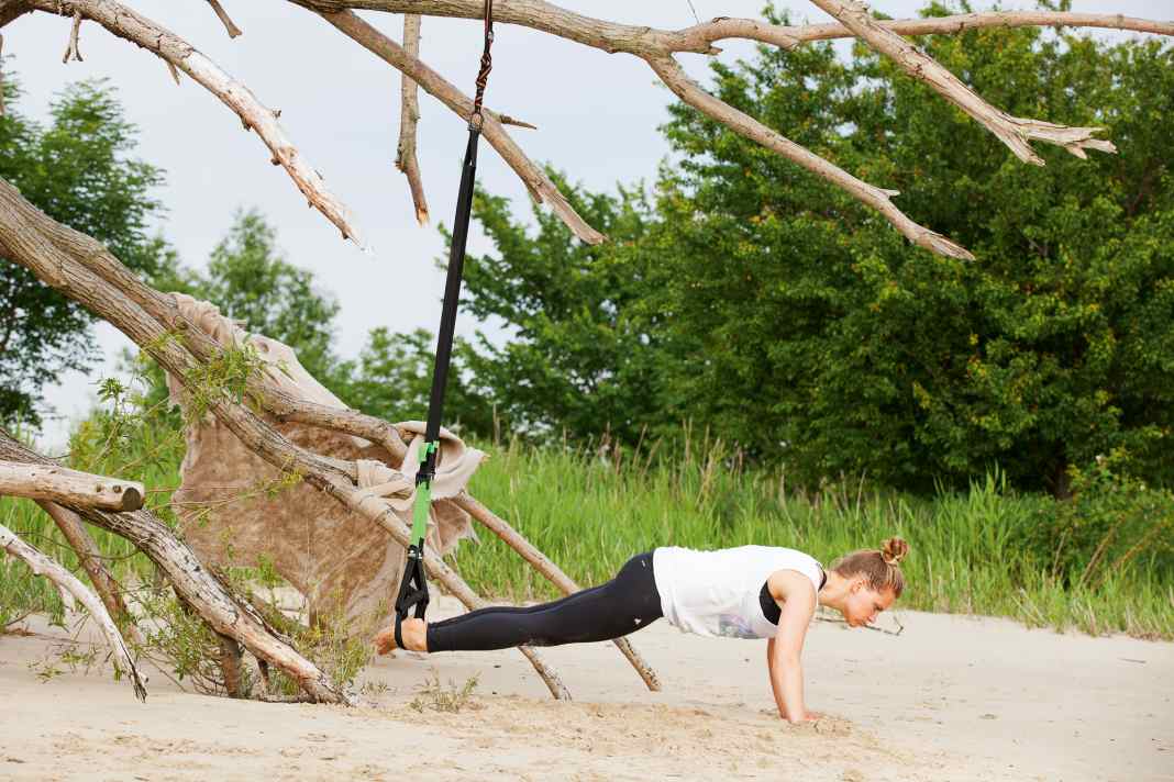 Step into both slings with your feet and assume the push-up position