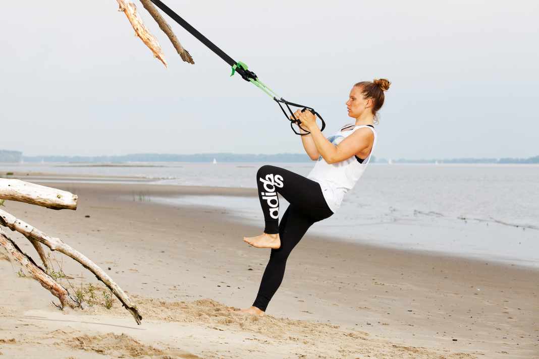 Pull the sling trainer with both arms and lean back slightly. The supporting leg is extended.