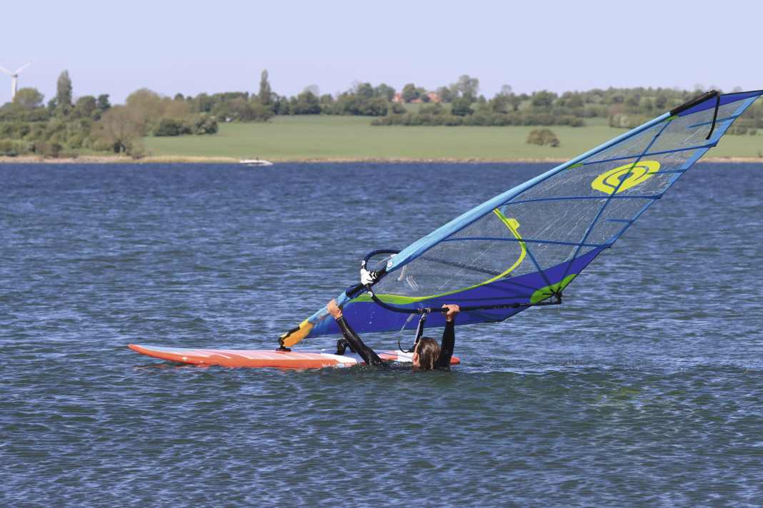The first step is to grip the mast with the front hand, then the lower leech with the rear hand.
