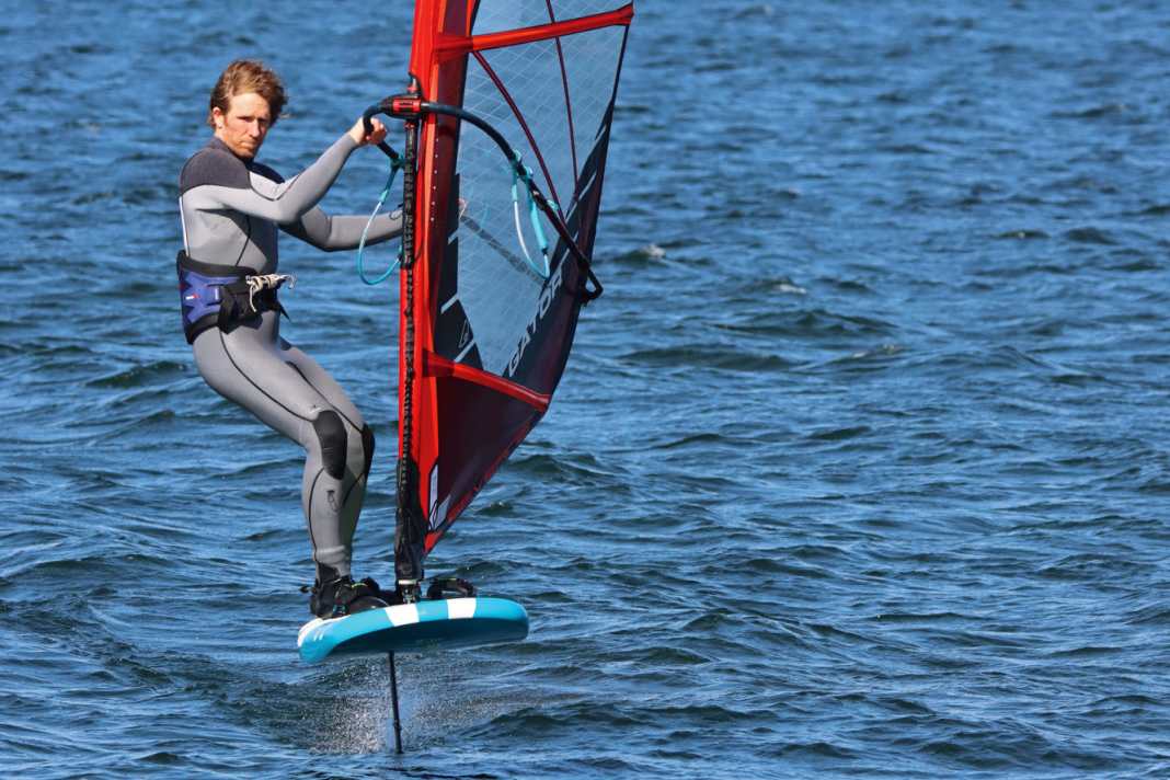 Check the free space downwind and unhook yourself from the harness. Take your back foot out of the loop and place it on the leeward edge of the board.