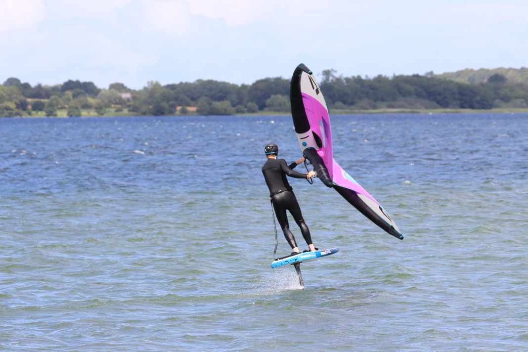 Ideally, you should practise on the side where you have the leash attached to your back hand. Start in switch stance, i.e. with your feet twisted, and get as much speed as possible. Note: The wind is coming from the left here