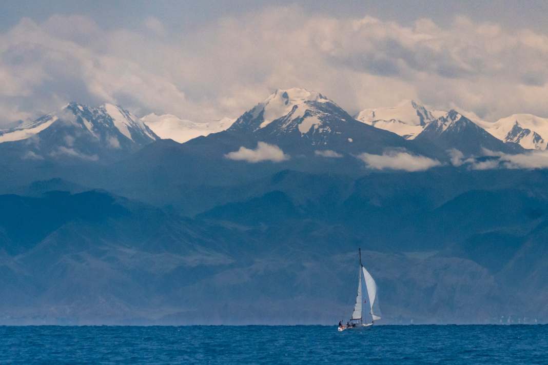 Platz 25: Eingekesselt – Carsten Bartsch. Kleine Yacht vor beeindruckender Bergkulisse. Der Yssykköl in Kirgistan ist ein riesiger Süßwassersee auf 1.600 m Höhe. Er ist eingerahmt von 5.000 m hohen Gebirgszügen