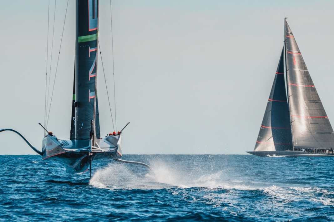 Die AC75 "Britannia" pflügt über den America's-Cup-Kurs von Barcelona. Am Horizont ist die schwedische J "Svea" zu sehen